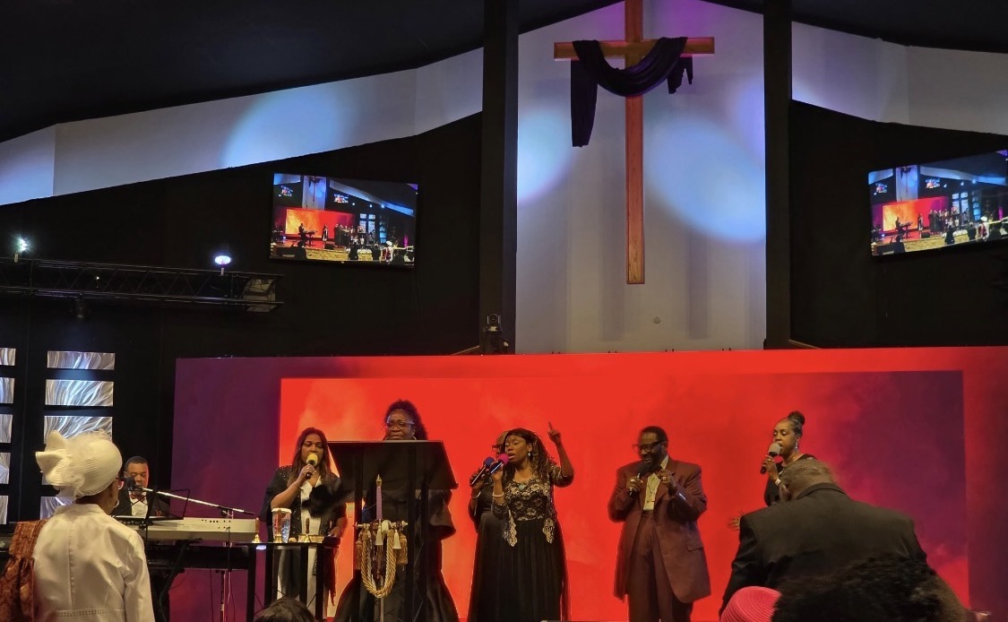 WOCA worship service with singers ministering beneath the cross